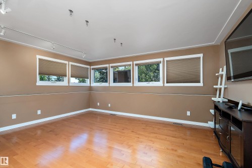 Spacious room featuring light wood-finish flooring, multiple windows with blinds, track lighting, and neutral wall tones - 4 Wentworth Crescent, St. Albert, AB 