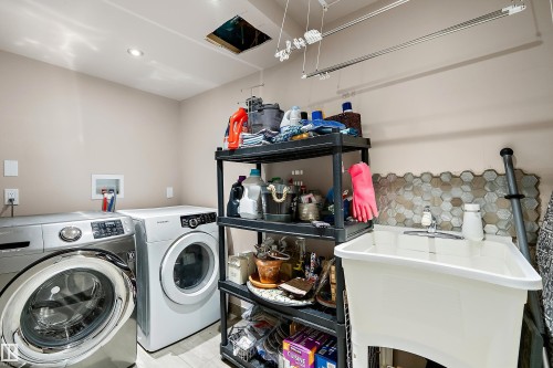 Dedicated laundry area featuring a utility sink with a chrome faucet, hexagonal tile backsplash, and recessed lighting - 4 Wentworth Crescent, St. Albert, AB 