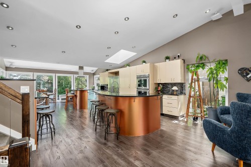 Open-concept kitchen and living area featuring wood-finish flooring, a vaulted ceiling, recessed lighting, and a skylight - 4 Wentworth Crescent, St. Albert, AB 
