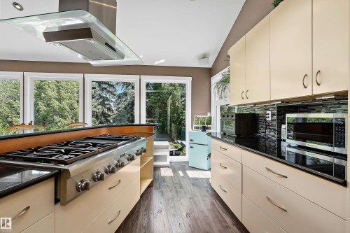 Kitchen featuring a stainless steel range, glass canopy range hood, and dark wood-finish flooring - 4 Wentworth Crescent, St. Albert, AB 