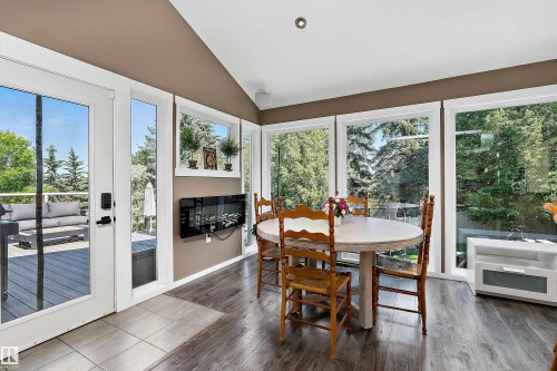 Sun-filled dining area featuring expansive windows, wood-finish flooring, and a vaulted ceiling - 4 Wentworth Crescent, St. Albert, AB 