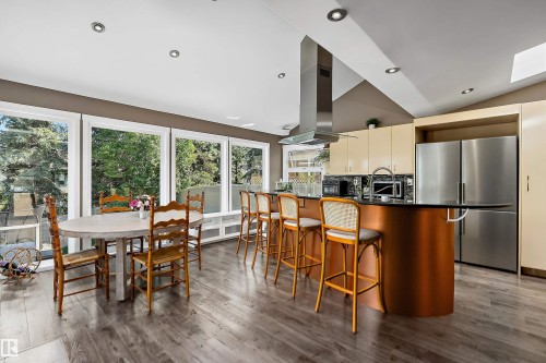 Contemporary kitchen featuring a curved island with seating for four, stainless steel appliances, and abundant natural light - 4 Wentworth Crescent, St. Albert, AB 