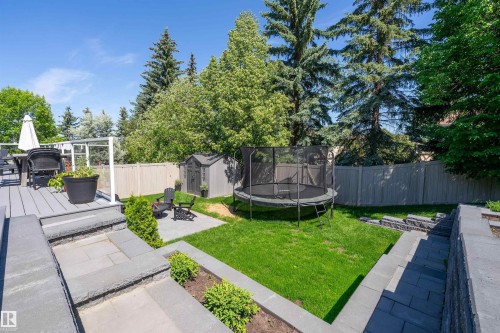 Multi-level backyard featuring a composite deck, stone patio, manicured lawn, and privacy fencing - 4 Wentworth Crescent, St. Albert, AB 