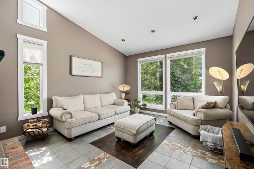 Vaulted ceiling living room featuring recessed lighting, a fireplace with a brick hearth, and a combination of tile and wood-finish flooring - 4 Wentworth Crescent, St. Albert, AB 