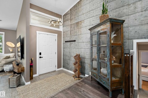 Entryway featuring a striking concrete accent wall, high vaulted ceilings, and a modern circular chandelier - 4 Wentworth Crescent, St. Albert, AB 