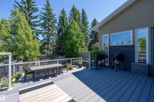 Spacious outdoor deck featuring multi-tone composite decking, white aluminum railing with clear panels, and mature perimeter trees - 4 Wentworth Crescent, St. Albert, AB 