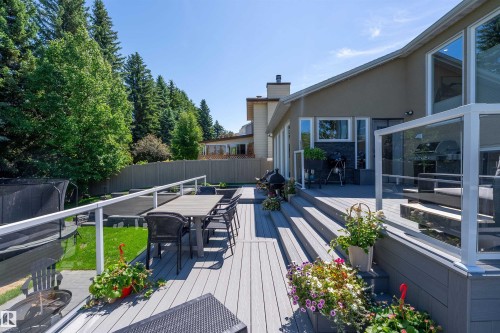 Multi-tiered composite deck featuring glass panel railings, direct lawn access, and ample space for outdoor entertaining - 4 Wentworth Crescent, St. Albert, AB 