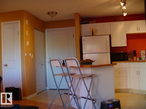 Kitchen featuring white cabinetry, wood-finish countertops, and track lighting - #116 10535 122 St Nw, Edmonton, AB - Indoor Photo Showing Kitchen