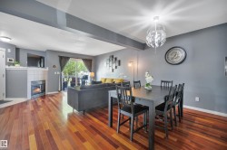 Open-concept living and dining area featuring wood-finish flooring, a corner fireplace with tile surround, and a sliding glass door leading to an outdoor space - 