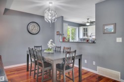 Spacious dining area featuring wood-finish flooring and a contemporary overhead light fixture - 