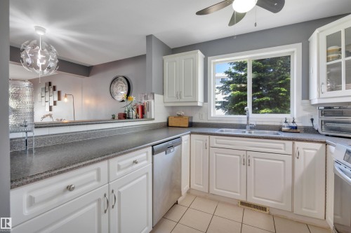 Kitchen featuring white cabinetry, a double basin sink, and a large window - #47 2505 42 St Nw, Edmonton, AB 