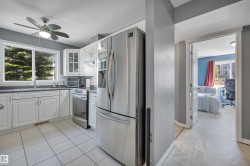 White shaker cabinetry with dark countertops, stainless steel appliances, and tile flooring - 