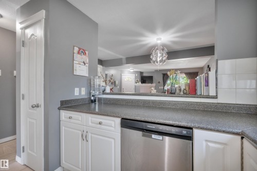 Kitchen featuring white cabinetry, dark speckled countertops, and a stainless steel Frigidaire dishwasher - #47 2505 42 St Nw, Edmonton, AB 