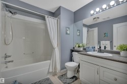 Bathroom with a white tub and shower combination, chrome fixtures, and a white vanity with a dark countertop - 