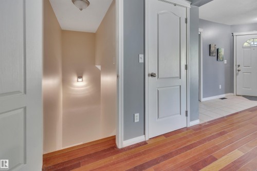 Hallway featuring wood-finish flooring, light gray walls, and white trim - #47 2505 42 St Nw, Edmonton, AB 