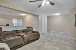 Spacious lower-level area featuring light-toned walls, recessed lighting, a ceiling fan with integrated lighting, and light grey patterned flooring - 