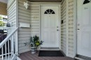 Entryway featuring a white paneled door with an arched transom window, wood-finish decking, and light-colored siding - #47 2505 42 St Nw, Edmonton, AB 