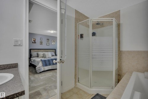 Bathroom featuring a corner shower enclosure, a bathtub, and a vanity with a countertop and undermount sink - #47 2505 42 St Nw, Edmonton, AB 