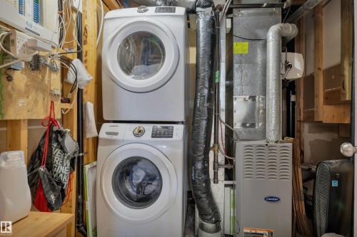 Dedicated utility area featuring a stacked washer and dryer, a forced-air furnace, and a water heater - #47 2505 42 St Nw, Edmonton, AB 