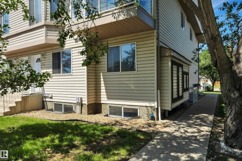 Exterior featuring light-colored horizontal siding, multiple windows, and a paved walkway - #47 2505 42 St Nw, Edmonton, AB 