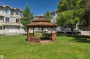 Freestanding wooden gazebo with a shingled roof, featuring built-in seating, set upon a green lawn - #47 2505 42 St Nw, Edmonton, AB 