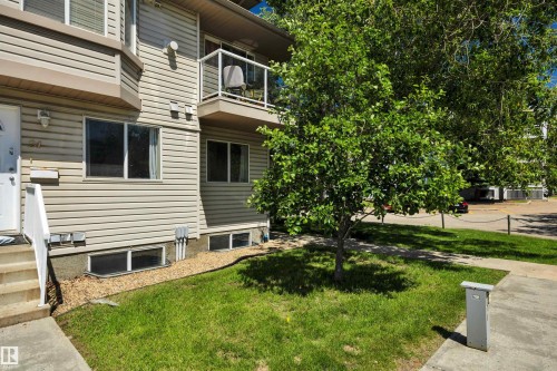 Multi-level townhouse exterior featuring beige siding, white trim, and a second-story balcony with glass railing - #47 2505 42 St Nw, Edmonton, AB 