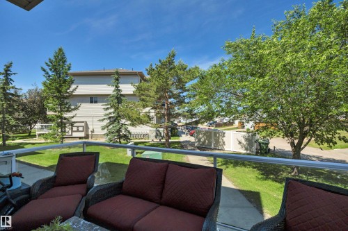 Balcony featuring a glass panel railing, a concrete surface, and surrounding mature trees - #47 2505 42 St Nw, Edmonton, AB 