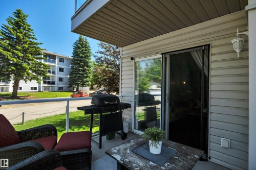 Outdoor patio featuring a sliding glass door, light-colored vinyl siding, and an overhead soffit - #47 2505 42 St Nw, Edmonton, AB 