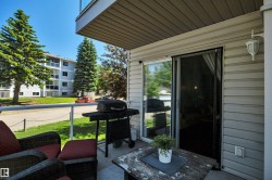 Outdoor patio featuring a sliding glass door, light-colored vinyl siding, and an overhead soffit - 
