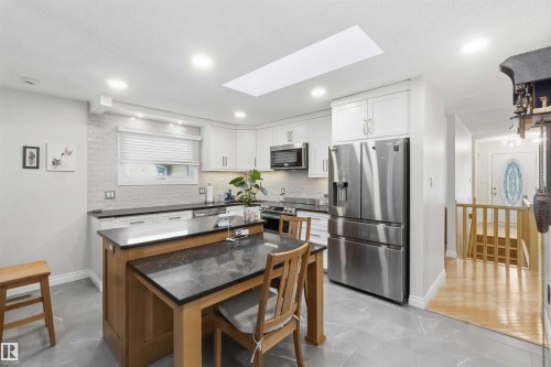 Contemporary kitchen featuring white cabinetry, dark countertops, and stainless steel appliances - 31 Gariepy Crescent, Edmonton, AB 