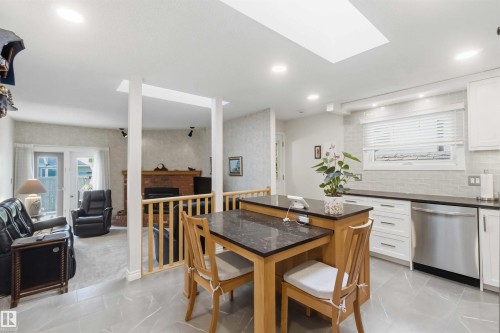 Contemporary kitchen featuring white cabinetry, dark countertops, stainless steel dishwasher, and a white subway tile backsplash - 31 Gariepy Crescent, Edmonton, AB 