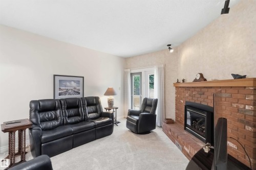 Living area featuring a brick fireplace with a wood mantle, track lighting, and a glass-paneled patio door - 31 Gariepy Crescent, Edmonton, AB 