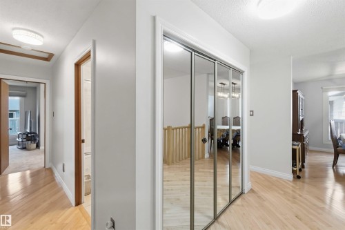Hallway featuring wood-finish flooring, mirrored closet doors, and recessed lighting - 31 Gariepy Crescent, Edmonton, AB 