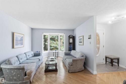 Living area featuring light wood-finish flooring and a prominent bay window - 31 Gariepy Crescent, Edmonton, AB 