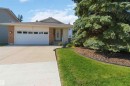 Exterior featuring a two-car garage with frosted window panels, brick accents, and a mature evergreen tree - 31 Gariepy Crescent, Edmonton, AB 