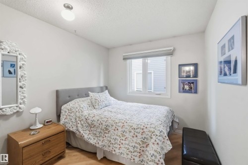 Bedroom featuring a prominent window, neutral wall paint, wood-finish flooring, and a textured ceiling - 31 Gariepy Crescent, Edmonton, AB 