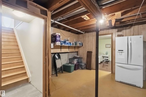 Basement area featuring a painted concrete floor, exposed wood ceiling joists, and vertical wood paneling - 31 Gariepy Crescent, Edmonton, AB 