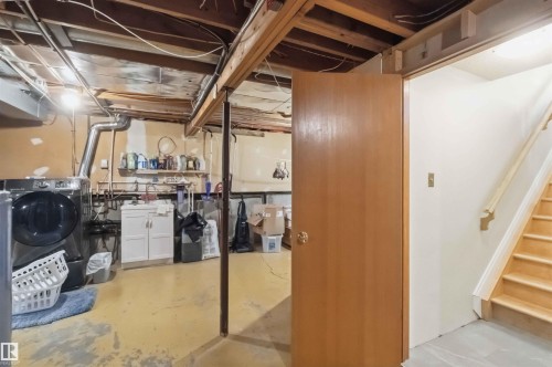 Utility space featuring exposed ceiling joists, concrete flooring, a laundry area with built-in cabinetry, and a natural wood staircase - 31 Gariepy Crescent, Edmonton, AB 