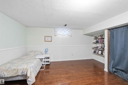 Interior room featuring wood-finish flooring, two-tone wall paint with a chair rail, and a textured ceiling - 31 Gariepy Crescent, Edmonton, AB 