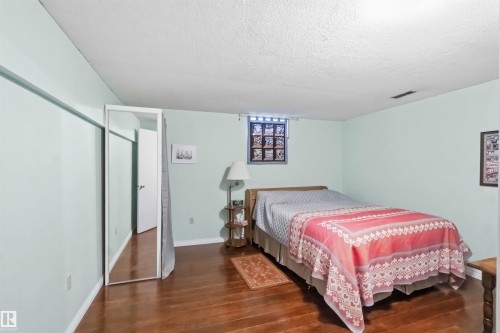 Bedroom featuring wood-finish flooring, light-toned walls, a textured ceiling, and a frosted window - 31 Gariepy Crescent, Edmonton, AB 