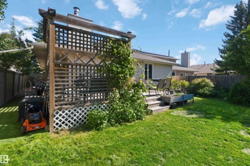 Spacious backyard featuring a wooden deck with steps, a wood lattice privacy screen, a raised garden planter, and a generously sized lawn area - 31 Gariepy Crescent, Edmonton, AB 