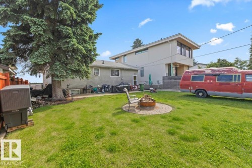 Expansive grassy lawn with a circular paver fire pit area - 4622 Ada Boulevard, Edmonton, AB 