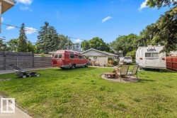 Spacious yard featuring a circular paver patio with a central fire pit - 