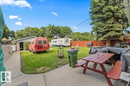 Expansive grass lawn with mature perimeter trees and a concrete patio - 4622 Ada Boulevard, Edmonton, AB 