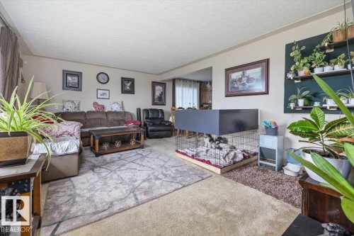 Spacious interior featuring neutral wall tones, textured ceiling, and a distinct built-in shelving unit - 4622 Ada Boulevard, Edmonton, AB 