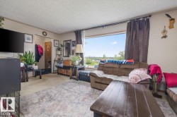 Living room featuring a large picture window, textured ceiling, and light-colored carpeting - 