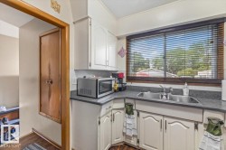 Kitchen featuring white cabinetry, grey countertops, and a double basin stainless steel sink - 