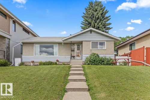 Front exterior featuring a concrete walkway, established front lawn, stucco and siding facade, covered entry, and mature landscaping - 4622 Ada Boulevard, Edmonton, AB 