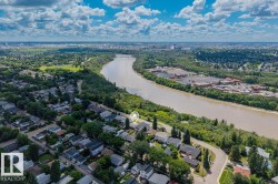 Aerial perspective showcasing a residential area bordered by a river and extensive green spaces - 