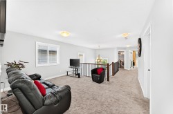 Open upper-level area featuring light-toned carpeting, a window with blinds, and white walls - 